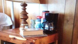 Un tavolo di legno con una lampada, un libro e una macchina per il caffè.