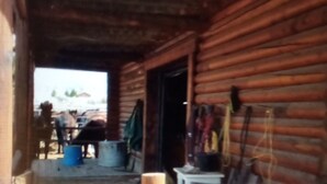 Un rustico chalet di legno con veranda, un tavolo e una sedia.