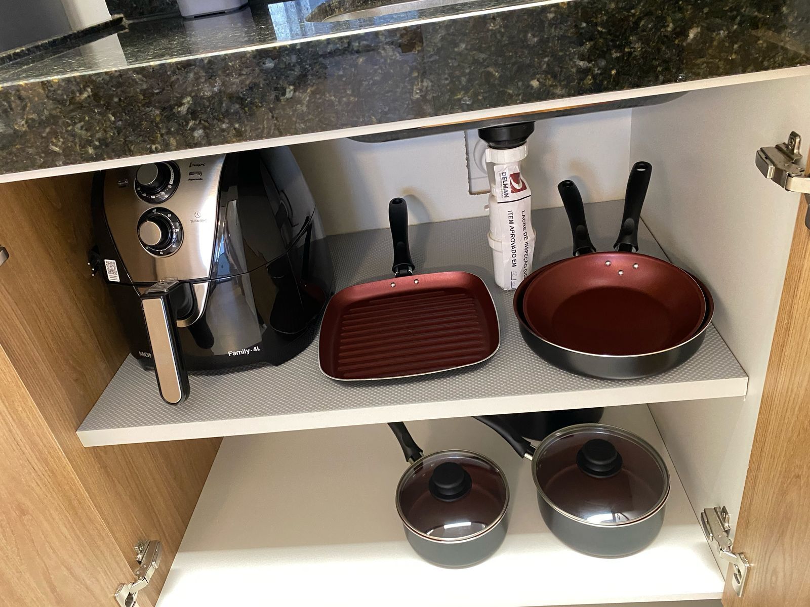 A kitchen with a stove, two frying pans, and two pots on the countertop.