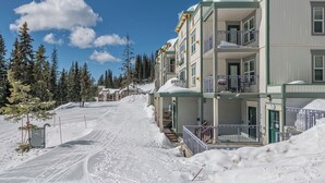 A multi-story hotel with balconies, a ski slope in the background, and snow-covered surroundings. - 2 bed/2 bath ground level condo, right on hike & bike trails, fireplace (Silver Star Mountain)