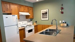 A kitchen with wooden cabinets, a white refrigerator, a stove, a sink, and a countertop. - 2 bed/2 bath ground level condo, right on hike & bike trails, fireplace (Silver Star Mountain)