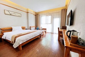 A hotel room with a wooden bed, a wooden table with a kettle, and a TV mounted on the wall. - Yicheng Hotel (Langzhong Ancient City Zhuangyuan Branch) (Langzhong)