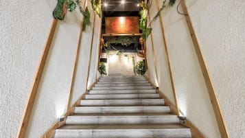 Una escalera con barandilla de madera que conduce a una habitación con pared de acento roja y plantas.
