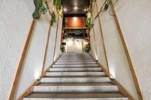 A staircase with a wooden handrail, leading to a room with a red accent wall and greenery. - Yicheng Hotel (Langzhong Ancient City Zhuangyuan Branch) (Langzhong)
