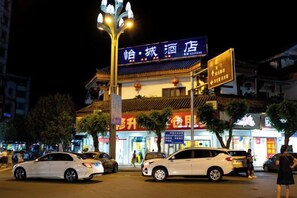 A hotel with a traditional facade, multiple signage, and a street view with parked cars. - Yicheng Hotel (Langzhong Ancient City Zhuangyuan Branch) (Langzhong)