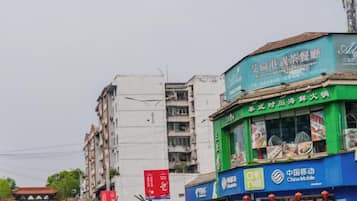 A street view with various commercial buildings, including a restaurant with a green awning and a blue storefront with a China Mobile logo.
