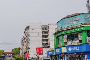 Straatbeeld met verschillende gebouwen, waaronder een restaurant met een groen luifel en een blauwe gevel met een China Mobile logo.