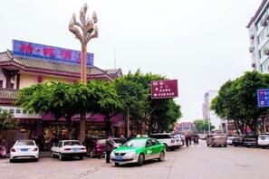A street with parked cars, a tree, and a building with a sign. - Yicheng Hotel (Langzhong Ancient City Zhuangyuan Branch) (Langzhong)