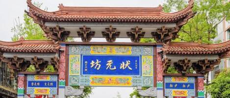 A traditional Chinese gate with intricate roof designs and a blue sign in the center.