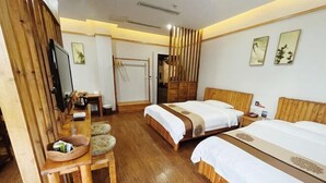Une chambre d’hôtel avec deux lits, un bureau en bois avec un panier, une télévision et une armoire.