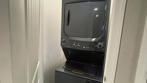 Een kleine kitchenette met een magnetron en oven, gelegen in een smalle gang met witte muren en een houten vloer.