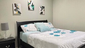 Een slaapkamer met een bed, nachtkastje, plafondventilator en drie kunstwerken aan de muur.