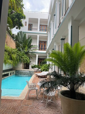 Une cour avec une piscine, des chaises longues et des plantes en pot.