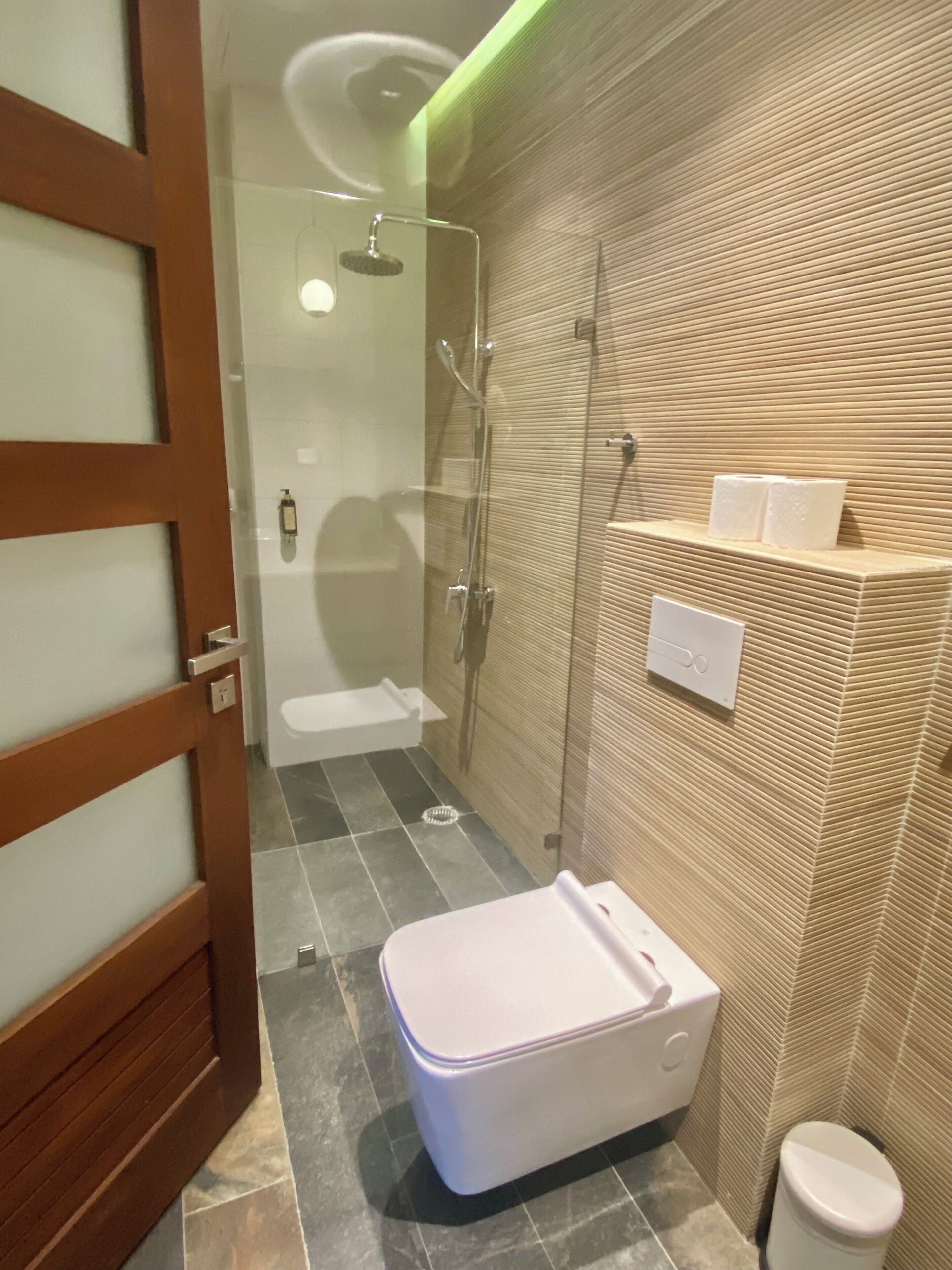A bathroom with a shower, toilet, and a small sink.