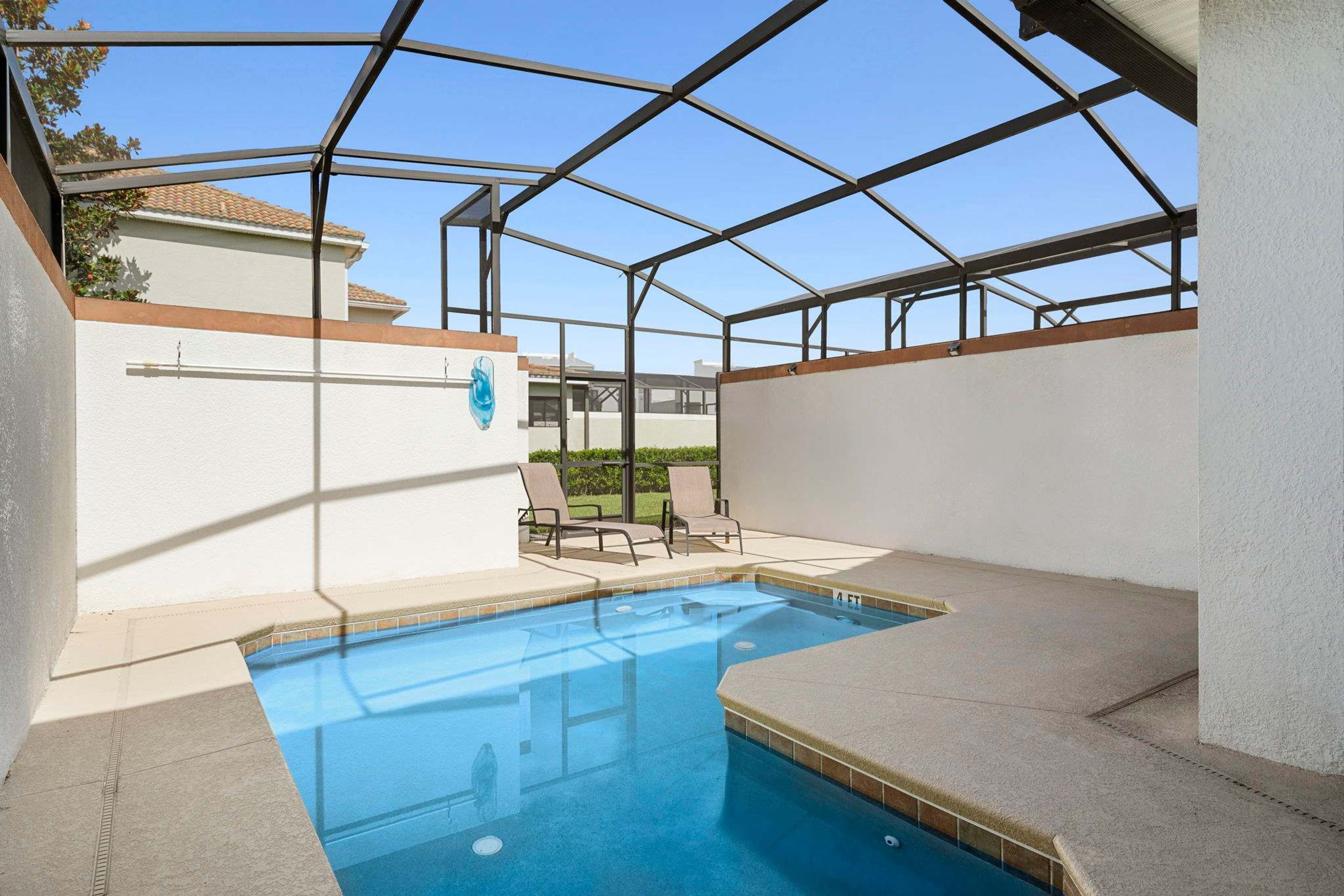 A covered outdoor swimming pool with lounge chairs and a clear view of the surrounding area.