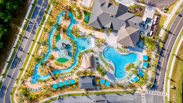 An aerial view of a resort with a large swimming pool, multiple lounge areas, and a parking lot. - Stylish Family Retreat With Themed Bedrooms (Kissimmee)