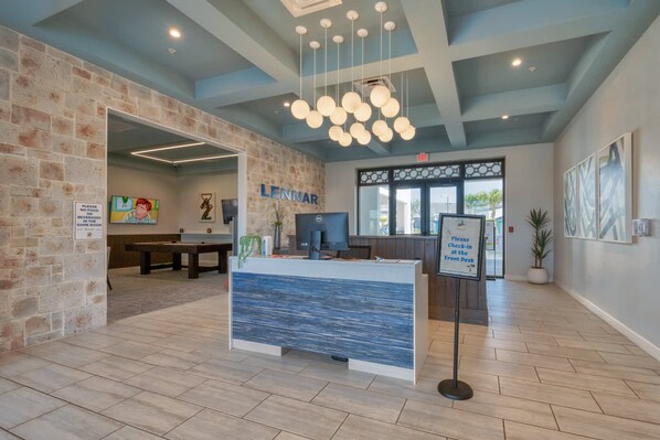 A reception area with a stone wall, a blue reception desk, and a sign instructing to check-in at the front desk.