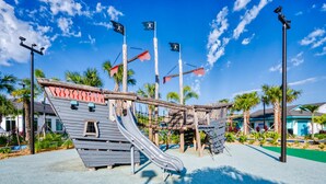 A playground with a pirate ship theme, including a slide and climbing structures. - Stylish Family Retreat With Themed Bedrooms (Kissimmee)