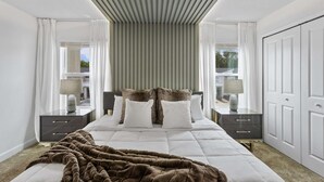 A hotel room with a large bed, two bedside tables with lamps, a wardrobe, and a view of the outside. - Stylish Family Retreat With Themed Bedrooms (Kissimmee)