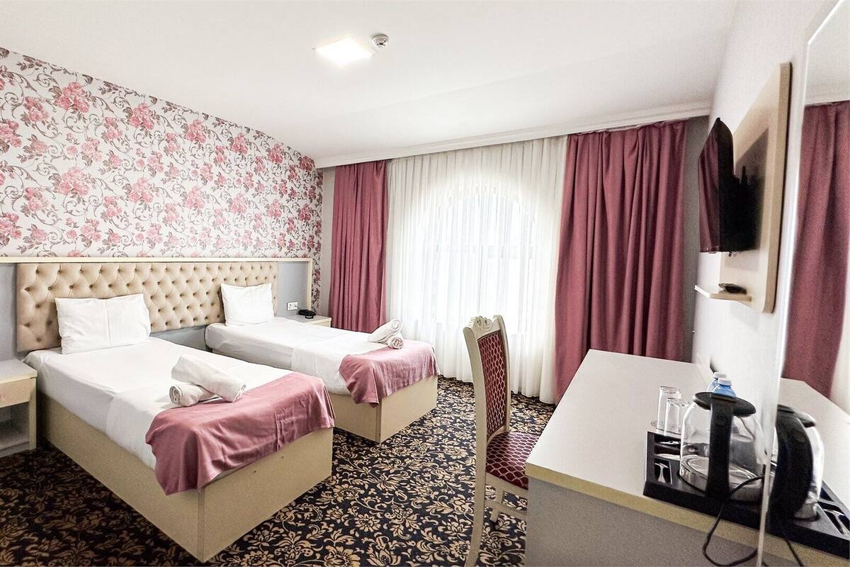 Habitación de hotel con dos camas, un escritorio, una silla, un televisor y un baño.