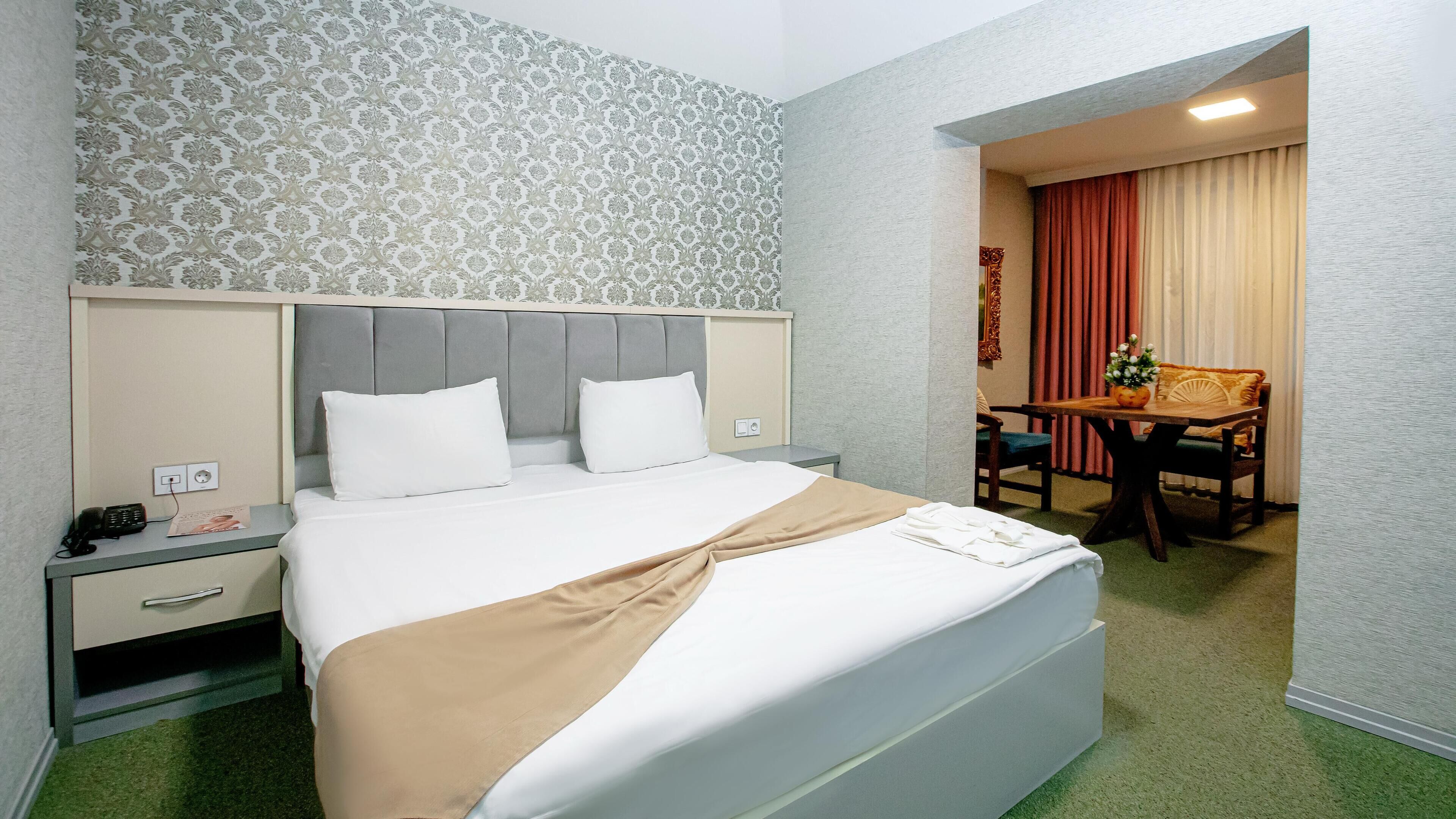 Ett hotellrum med en säng, sängbord, ett skrivbord och en stol.