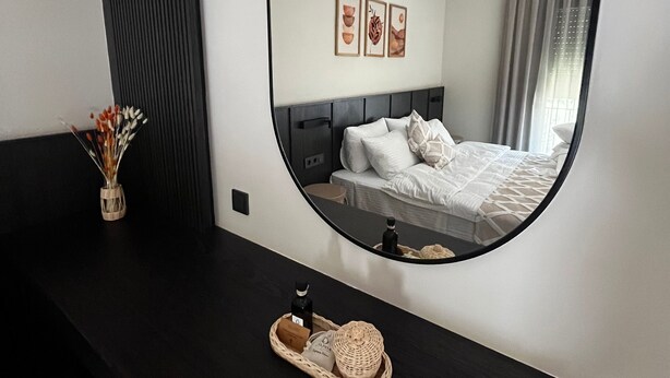 A modern hotel room with a large mirror reflecting the bed and artwork on the wall. - Urlivia (Urla)