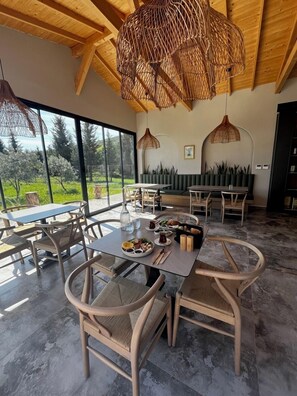 A spacious dining area with a high ceiling, large windows, and a view of the outdoors. - Urlivia (Urla)