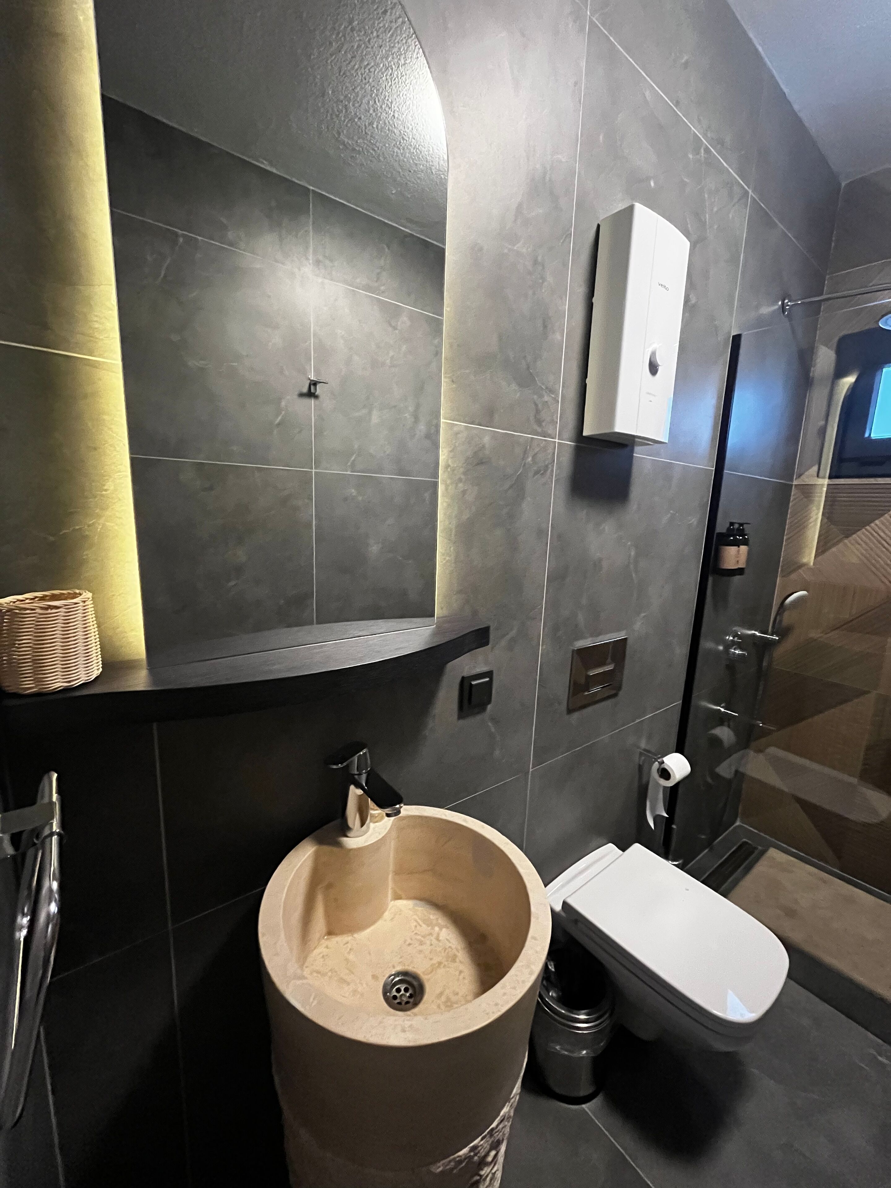 Un baño moderno con un lavamanos grande, inodoro y zona de ducha.