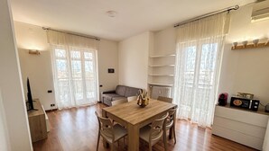 A spacious living area with a wooden dining table, chairs, a sofa, and a kitchen area with a microwave and toaster. - SkyLoft Bergamo - Chic Penthouse with Unique Panorama (Bergamo)