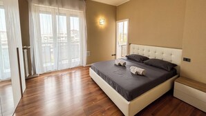 A bedroom with a large bed, a window with curtains, a radiator, and a wall-mounted light. - SkyLoft Bergamo - Chic Penthouse with Unique Panorama (Bergamo)