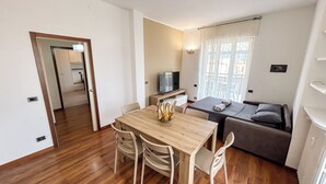 A compact room with a wooden dining table, two chairs, a sofa, and a television. - SkyLoft Bergamo - Chic Penthouse with Unique Panorama (Bergamo)