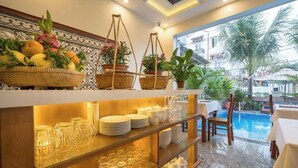 A hotel bar area with shelves of glassware, a fruit basket, and potted plants. - Superior King room - Hoi An Discovery Villa (Cam Chau ward)