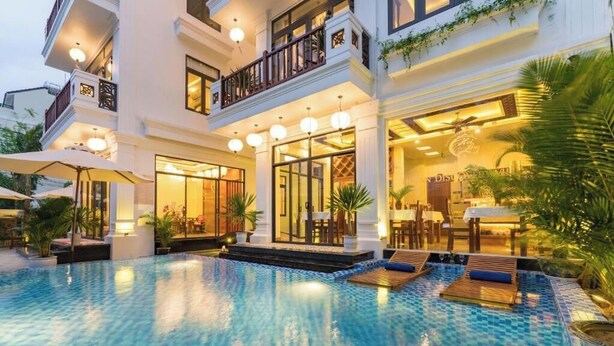 A hotel with a large outdoor swimming pool, multiple balconies, and well-lit interior spaces. - Superior King room - Hoi An Discovery Villa (Cam Chau ward)