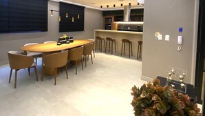 Una cocina moderna con una isla central, iluminación colgante y una zona de comedor con una mesa redonda y sillas.