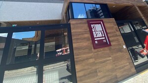 Un edificio moderno con un letrero llamativo que dice 'STUDIOS DESIGN 3' y una amplia entrada de vidrio.