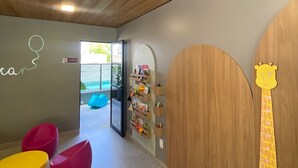 Zona de juegos para niños con asientos coloridos y una pared de madera decorada con una jirafa.