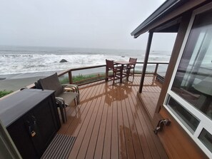 Una terraza de madera con una mesa y sillas con vista al océano.