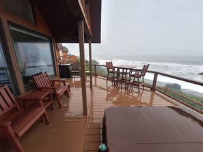 Una terraza de madera con mesa y sillas, con vista al océano.