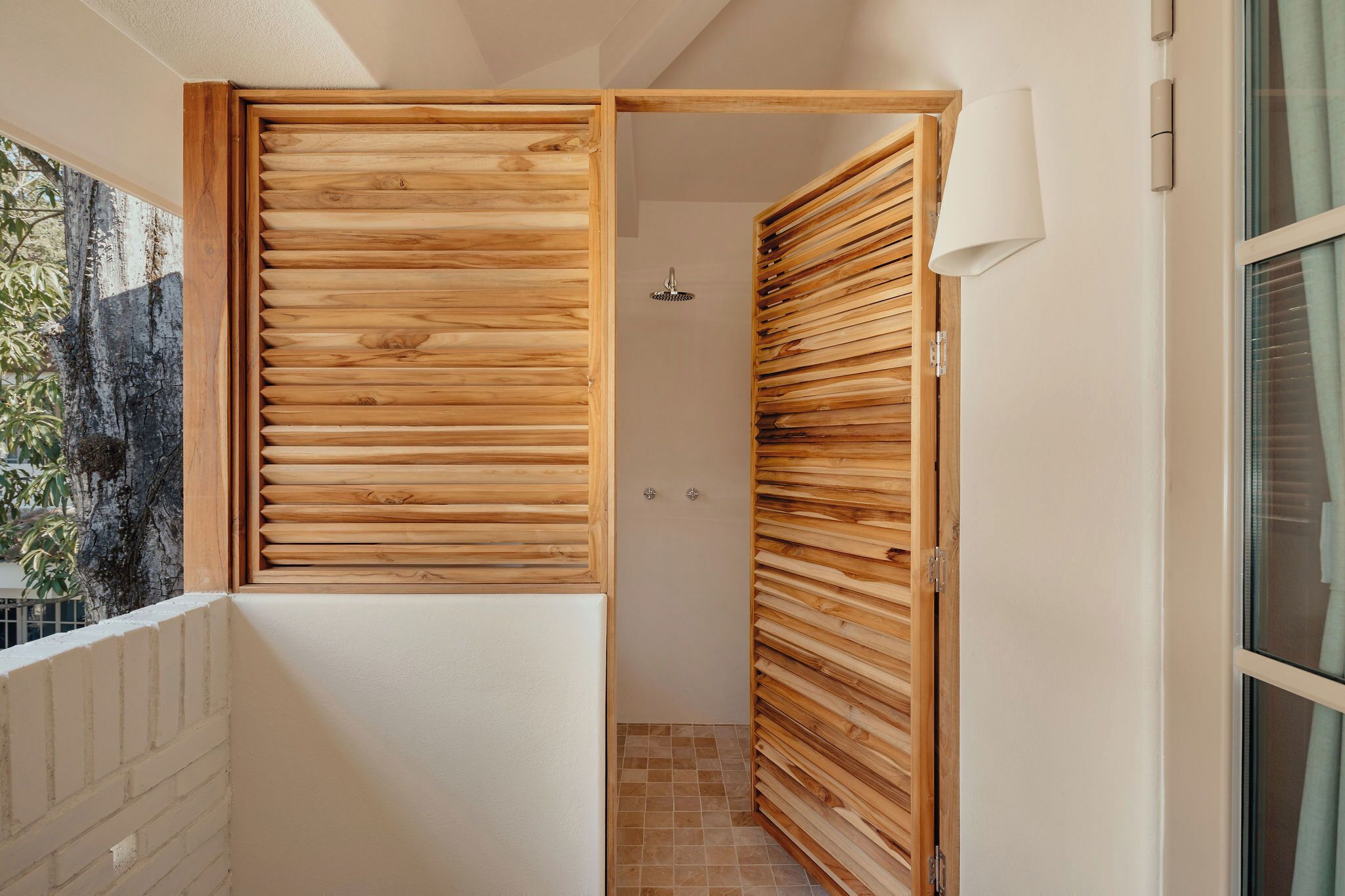 Een badkamer met houten paneeldeuren, een douche en een betegelde vloer.