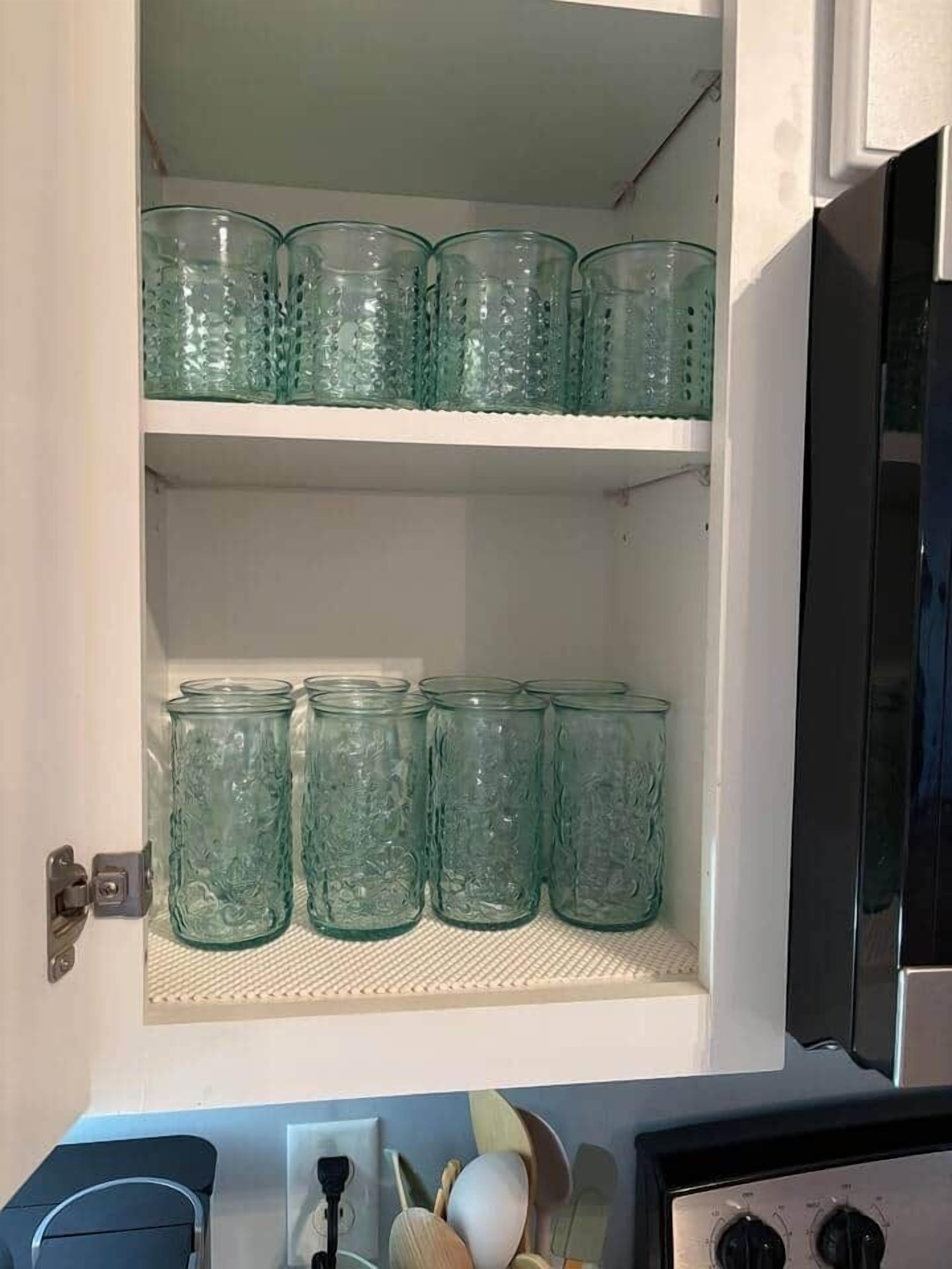 Ein Küchenschrank mit zwei Einlegeböden, einer mit klaren Glasbehältern und der andere mit grünen Glasbehältern.