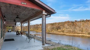 Un espace extérieur abrité, doté d’un sol en béton, de bancs et offrant une vue sur une rivière.