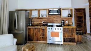Una cocina moderna con un refrigerador de acero inoxidable, estufa a gas y armarios de madera. Hay lámparas colgantes de mimbre sobre la encimera.