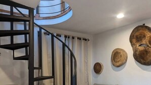 Un salon moderne avec un escalier en colimaçon, un canapé gris et des éléments de décoration en bois.