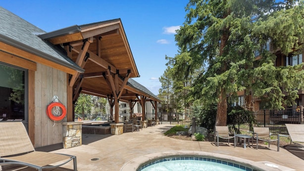 Un espace piscine agrémenté d’une pergola en bois, de chaises longues et d’un poste de surveillance pour les sauveteurs.