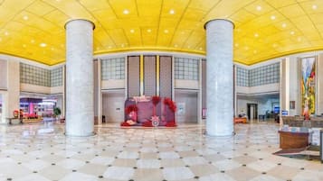 Un hall d’entrée spacieux, doté d’un plafond haut, de grandes colonnes et d’un motif à carreaux sur le sol.