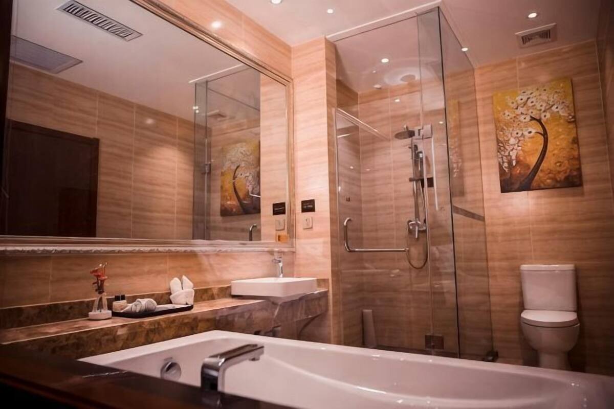 A modern bathroom with a glass shower enclosure, a large mirror, and a bathtub.