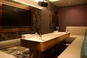 A modern bathroom with a marble vanity, a large mirror, and a seating area.