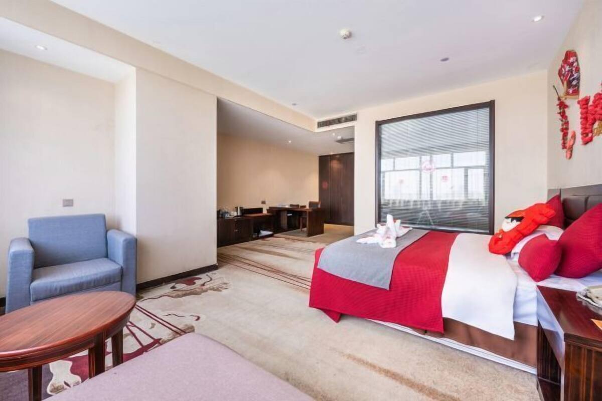 A hotel room with a bed, a desk, a chair, and a small table.