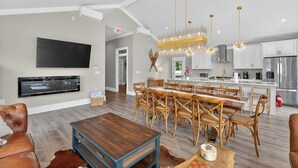 Un salón espacioso con un televisor de pantalla plana grande, una mesa de comedor de madera y asientos cómodos.