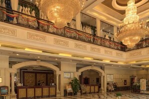 Eine beeindruckende Lobby mit Kronleuchtern, einer Rezeption und einer Treppe.